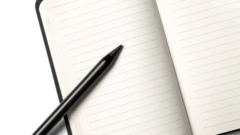 A notebook with a pencil resting on top, photographed against a clean white background